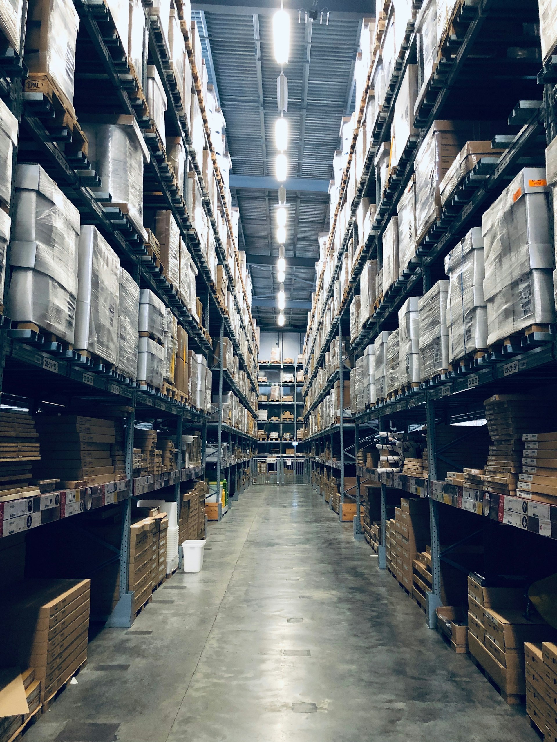Tall narrow-aisle warehouse racking running to the ceiling, the kind of high-density storage Superior Engineering's attachments make possible.